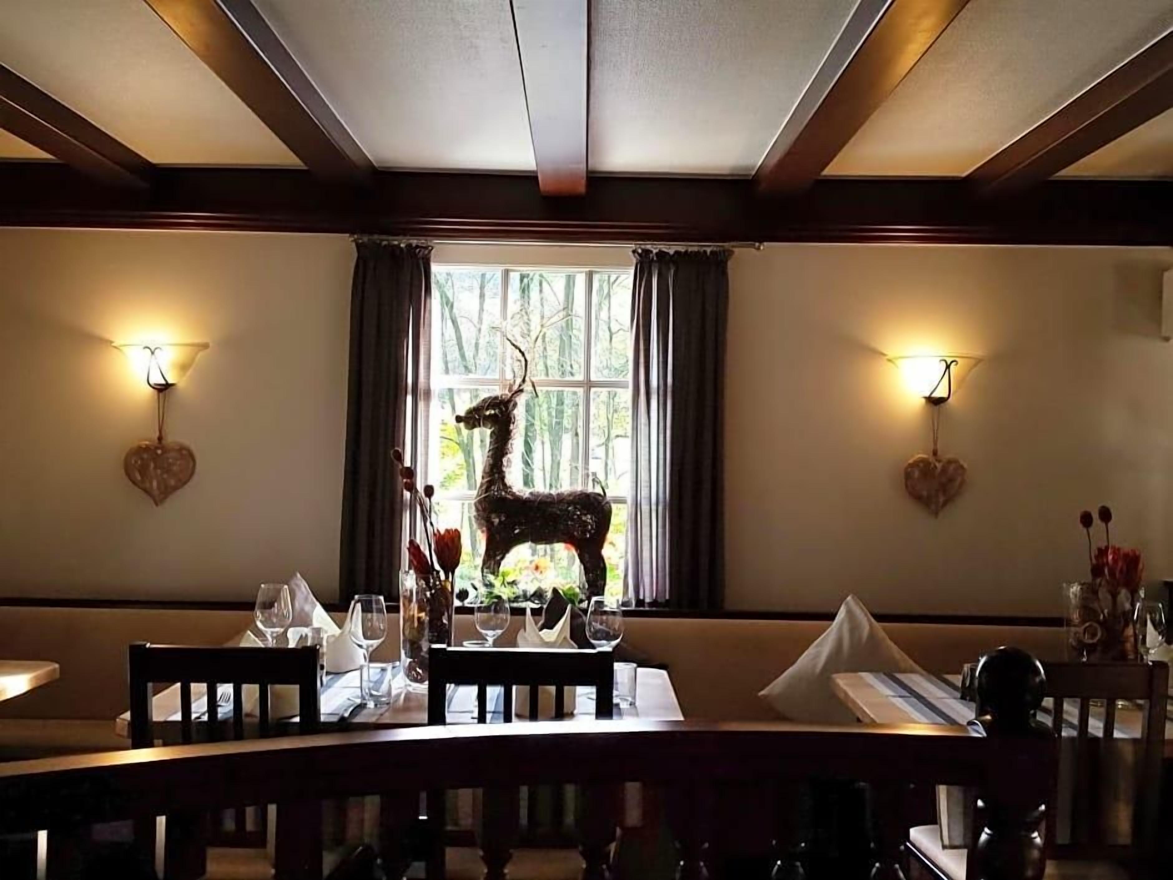 A dining area with a table set for two, a decorative deer sculpture, and heart-shaped wall decorations.