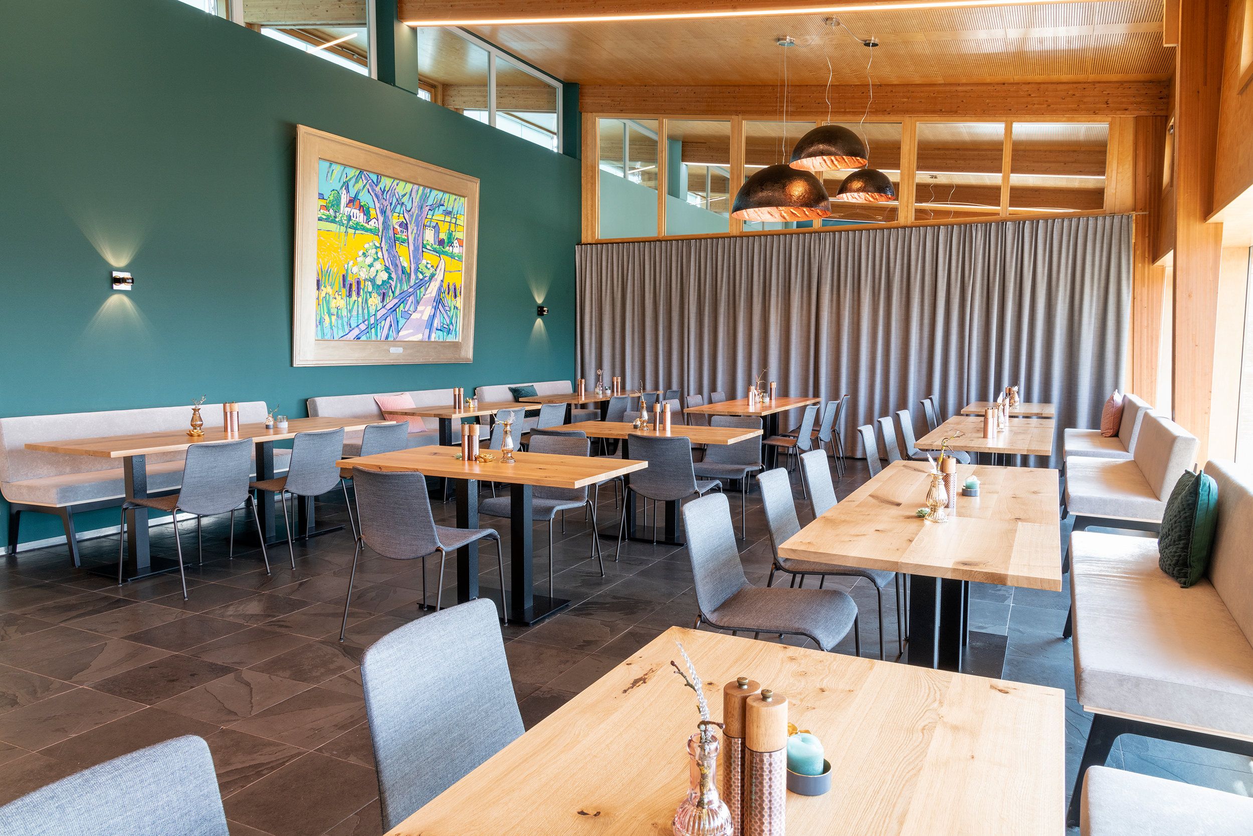 A modern dining area with multiple tables and chairs, a large abstract painting on the wall, and a view of the outdoors through large windows.