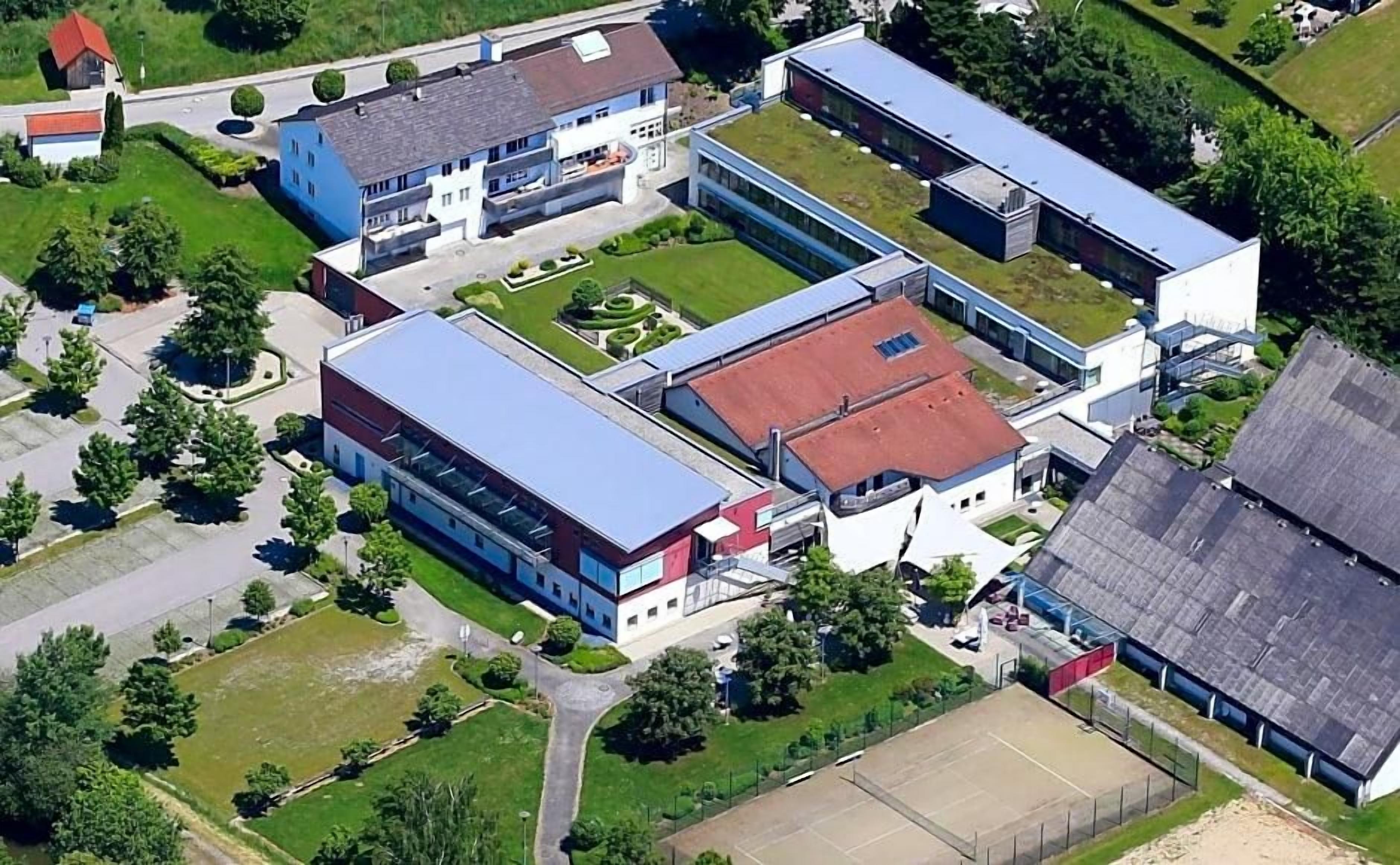 An aerial view of a campus with multiple buildings, green spaces, and a parking area.