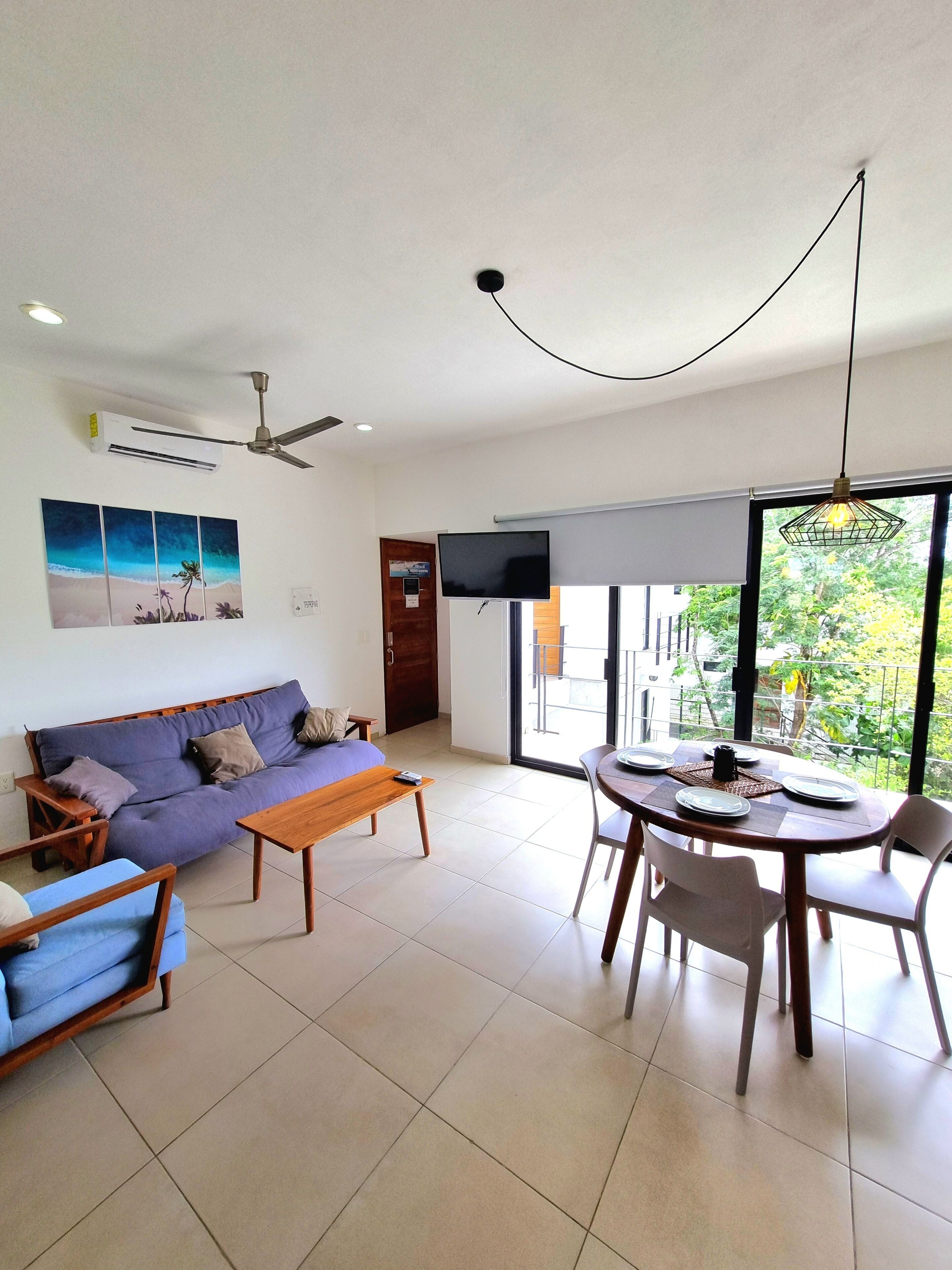 A modern living room with a sofa, a coffee table, and a dining area with chairs and a table set for two.
