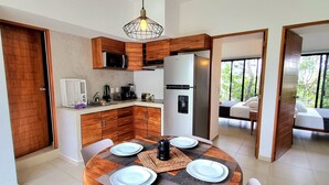 A modern kitchen with wooden cabinets, a stainless steel refrigerator, and a dining area with a round table and chairs. - Mi Tulum (Tulum)