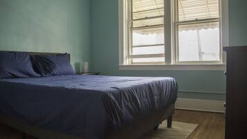 Un dormitorio con cama, ventana y cómoda.