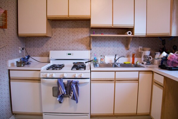 A compact kitchen with a stove, sink, and basic countertop appliances.