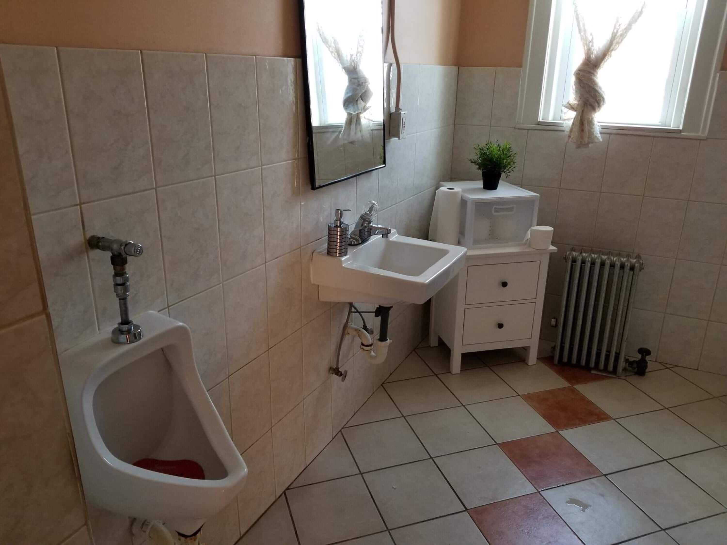A bathroom with a urinal, sink, and mirror.