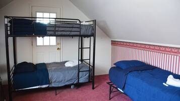 A dormitory room with two bunk beds, a door, and a window.