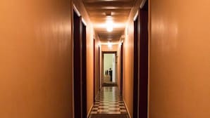 Un pasillo de hotel con piso a cuadros, alfombra roja y puertas a ambos lados.
