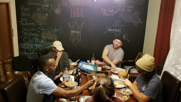 Un grupo de personas cenando en una mesa con una pizarra que muestra nombres y el logotipo de un hotel.