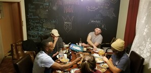 A group of people dining at a table with a chalkboard displaying names and a hotel logo.