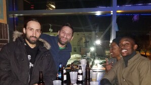 Tres personas sentadas en una mesa con varias botellas y vasos.