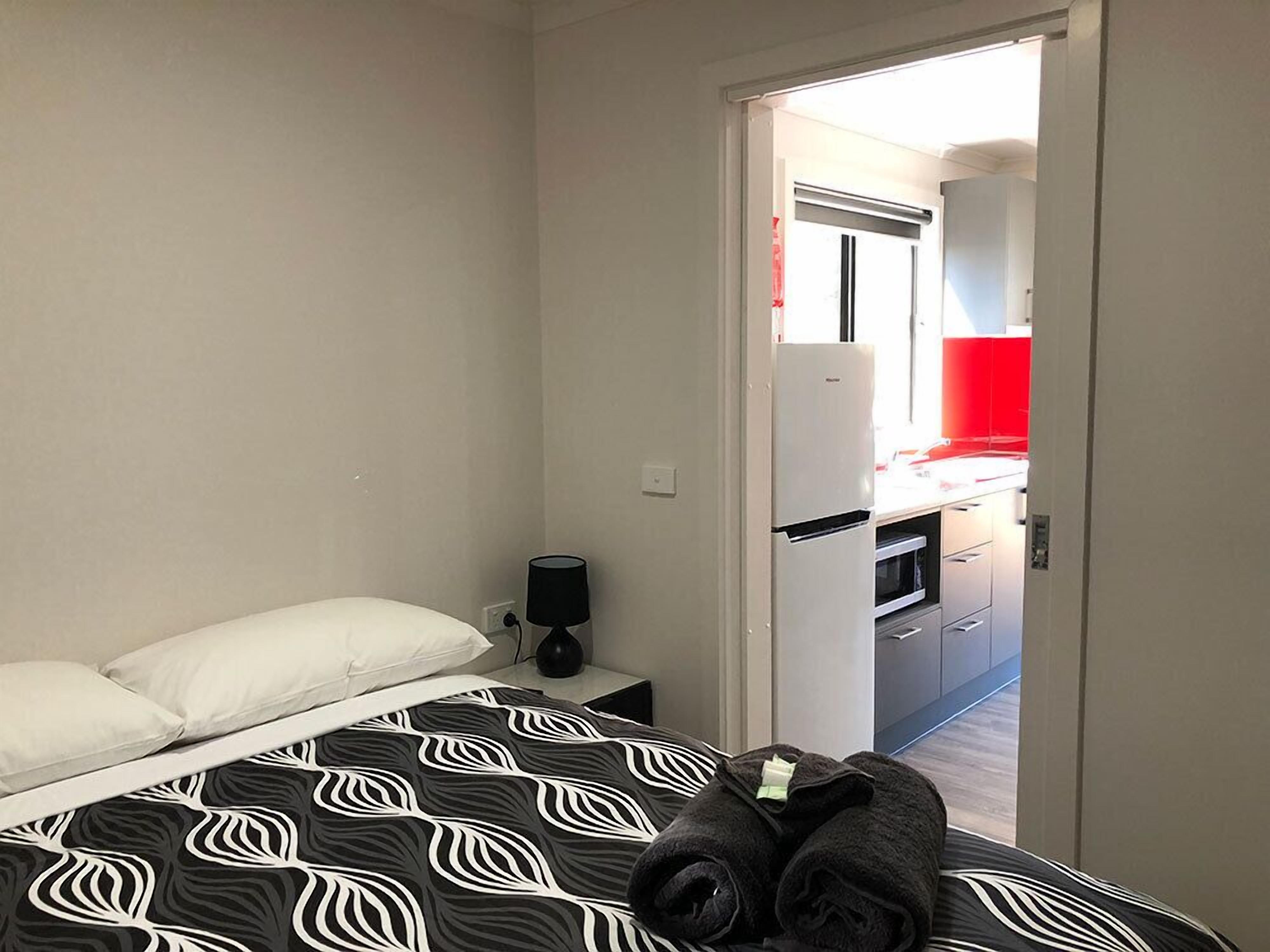 A bedroom with a bed, a nightstand, and a rolled-up towel.