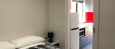 Un dormitorio con una cama, una mesita de noche y una toalla enrollada.