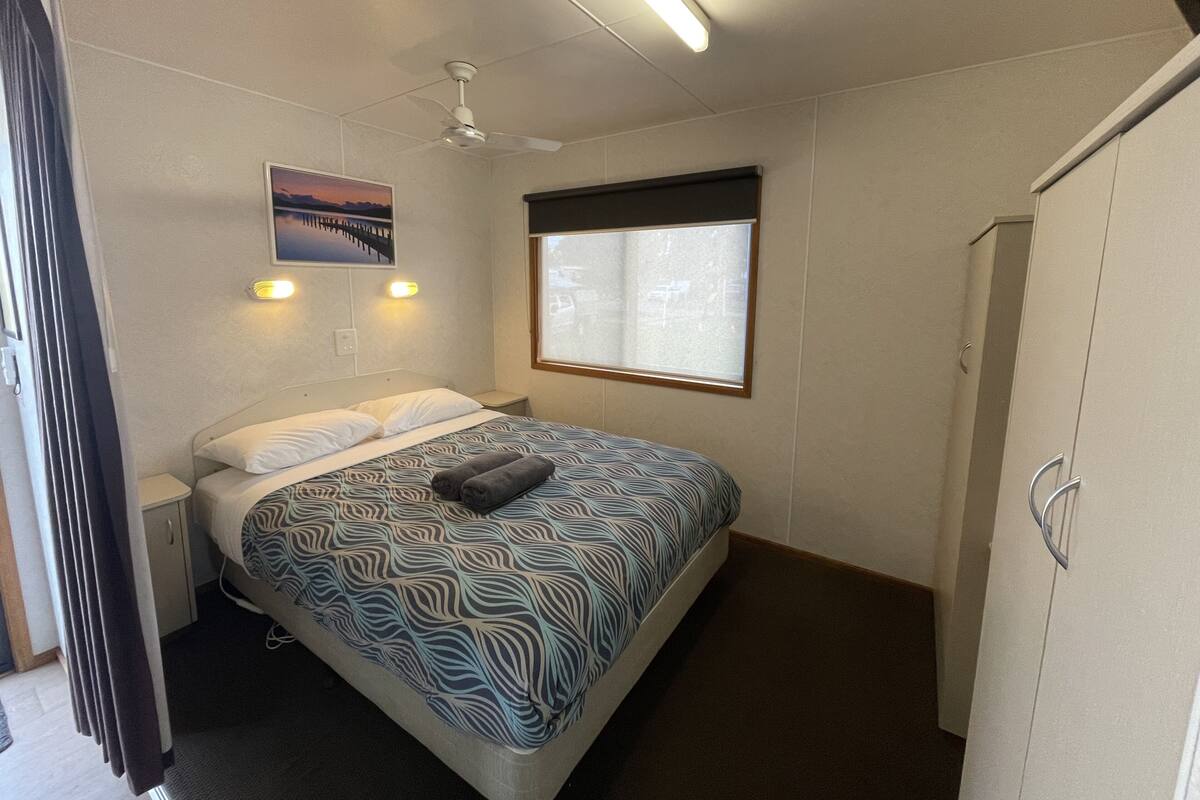 Ein Schlafzimmer mit Bett, Deckenventilator, Fenster und Kleiderschrank.