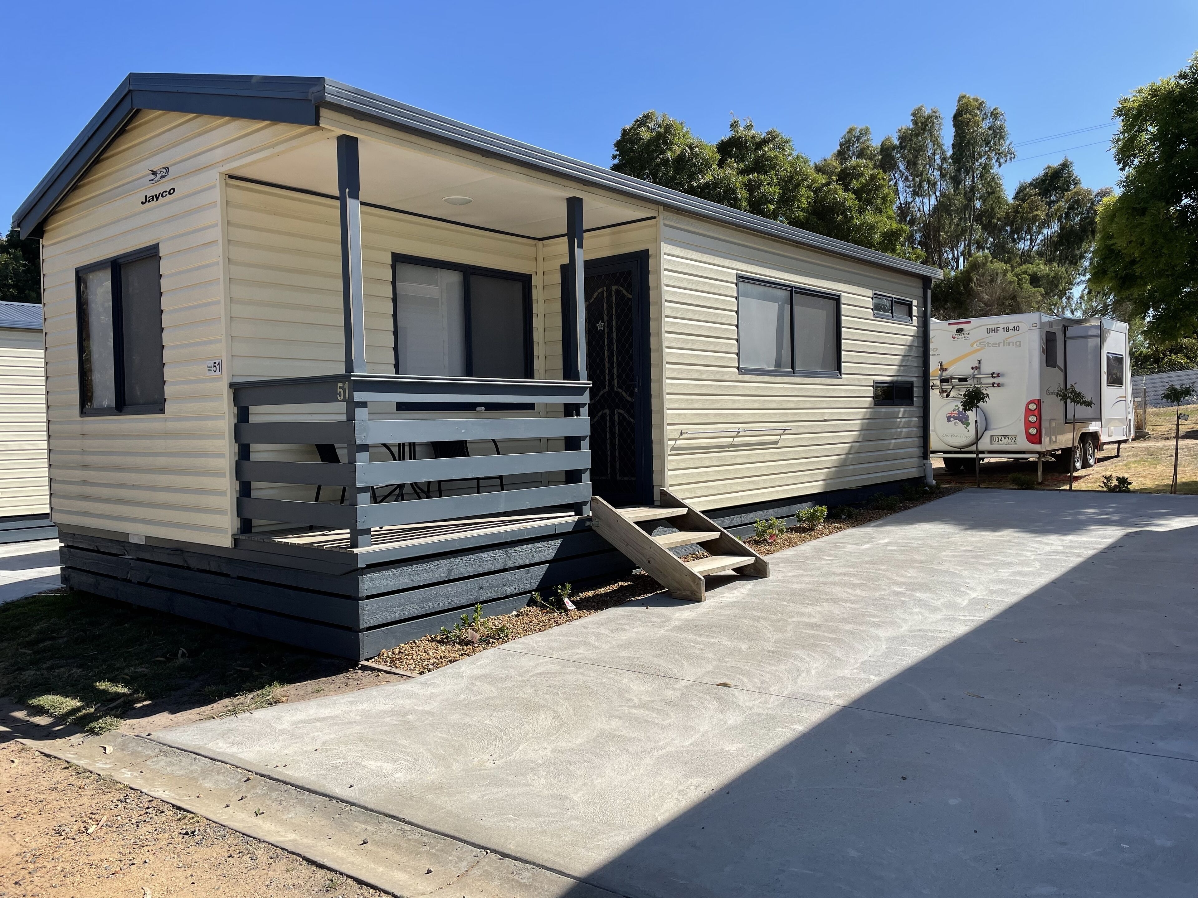 A mobile home with a porch and a ramp, adjacent to a utility vehicle.