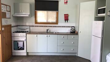 A compact kitchen with a stove, oven, sink, and a refrigerator.