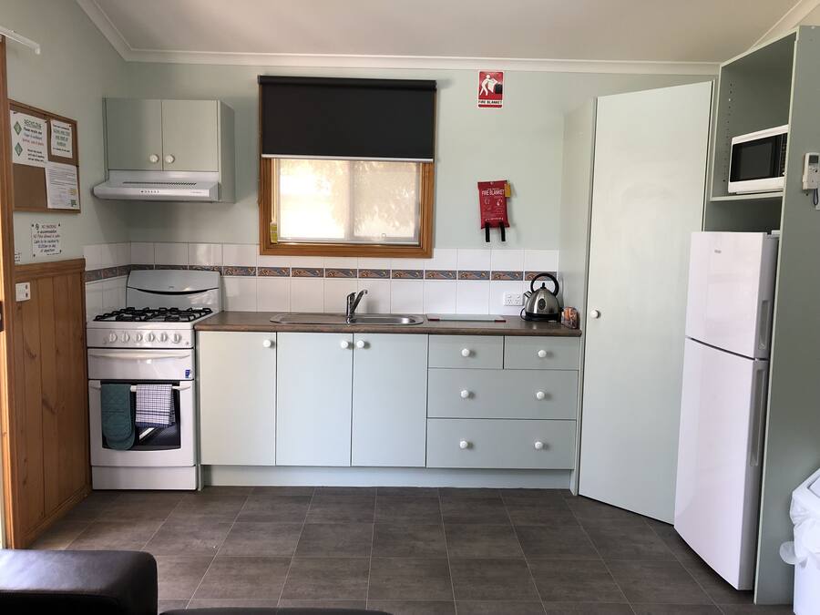 A compact kitchen with a stove, oven, sink, and a refrigerator.