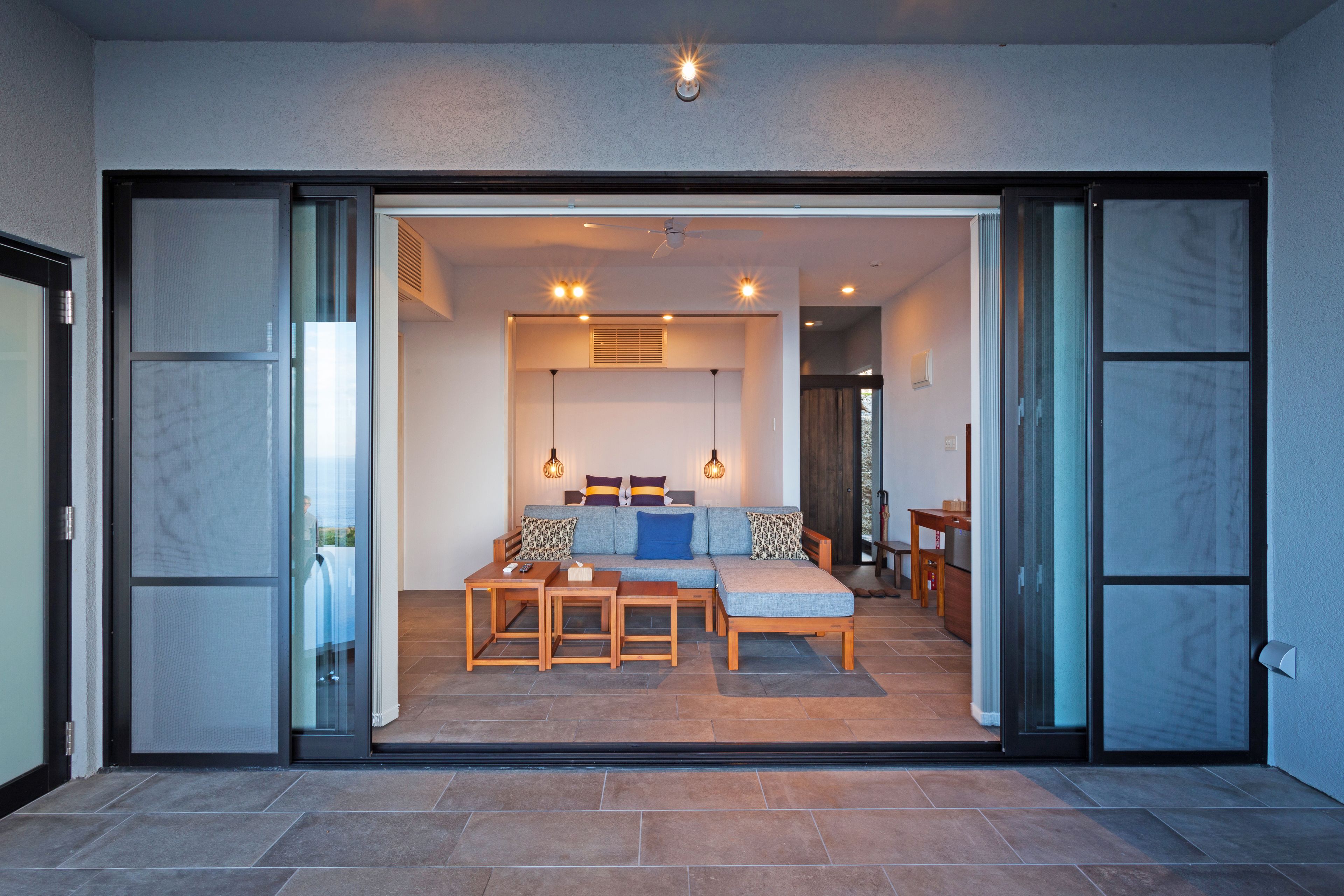 Una sala de estar moderna con sofá, mesa de centro y sillas, un comedor con mesa y sillas, y una cocina con encimera y armarios.
