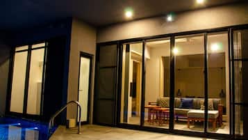 A modern hotel room with a glass door leading to a dining area, a small pool, and a staircase.