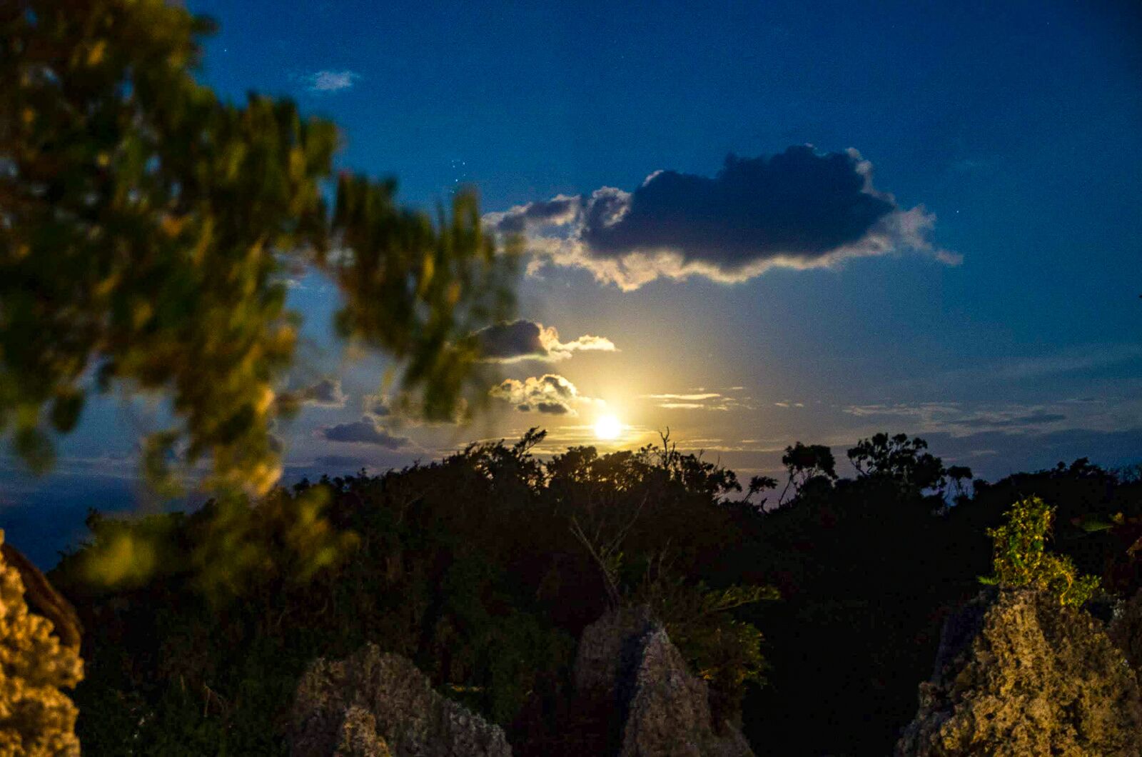 A sunset over a forested landscape with rocky outcrops.