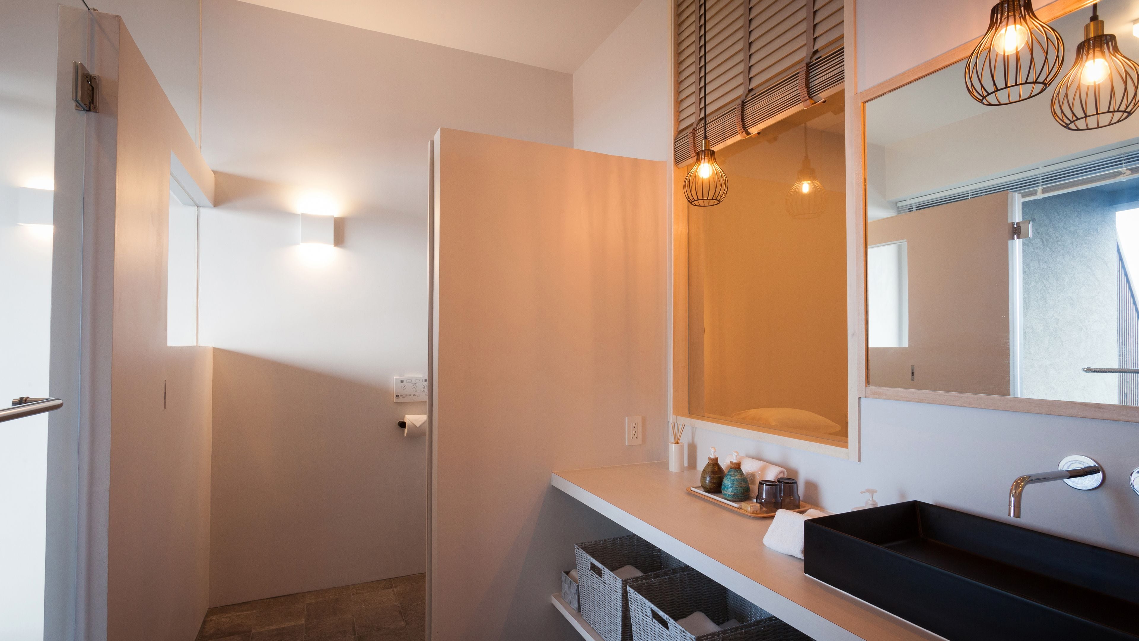 A modern bathroom with a large mirror, a black sink, and a shower area.