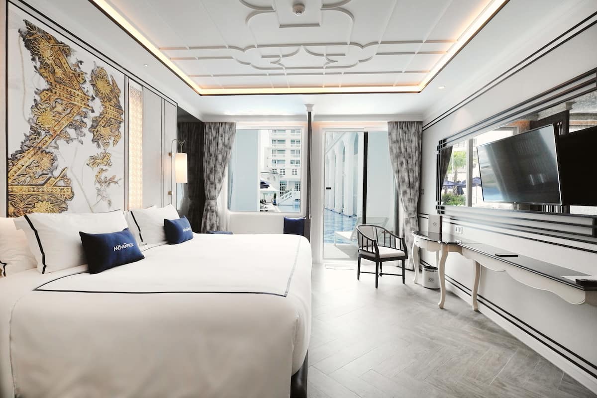 Une chambre d’hôtel moderne dotée d’un grand lit, d’une télévision et d’un balcon offrant une vue sur la ville.