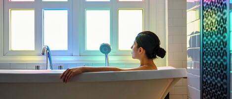 A bathtub with a window view, a faucet, and a round object on the edge.