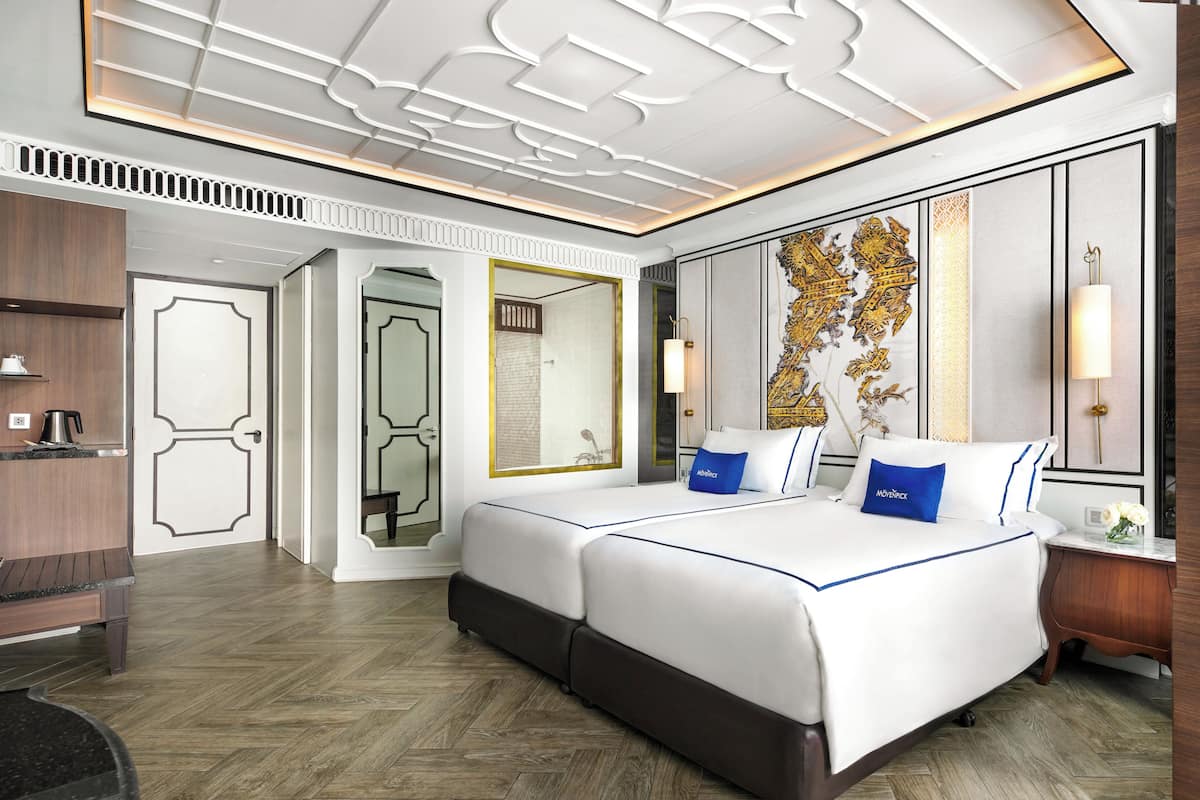 Une chambre d’hôtel avec deux lits, un grand miroir, un mur décoratif et un plancher en bois.
