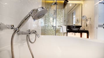 Une salle de bain moderne dotée d’une grande baignoire, d’une douche avec un pommeau de douche amovible et d’une cabine de douche en verre.