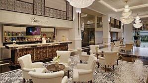 Een luxueuze lobby met een bar, elegante kroonluchters en een vloer met een patroon.