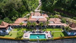 Et stort resort med flere bygninger, en central pool med et yin-yang symbol og frodigt grønt område omkring.