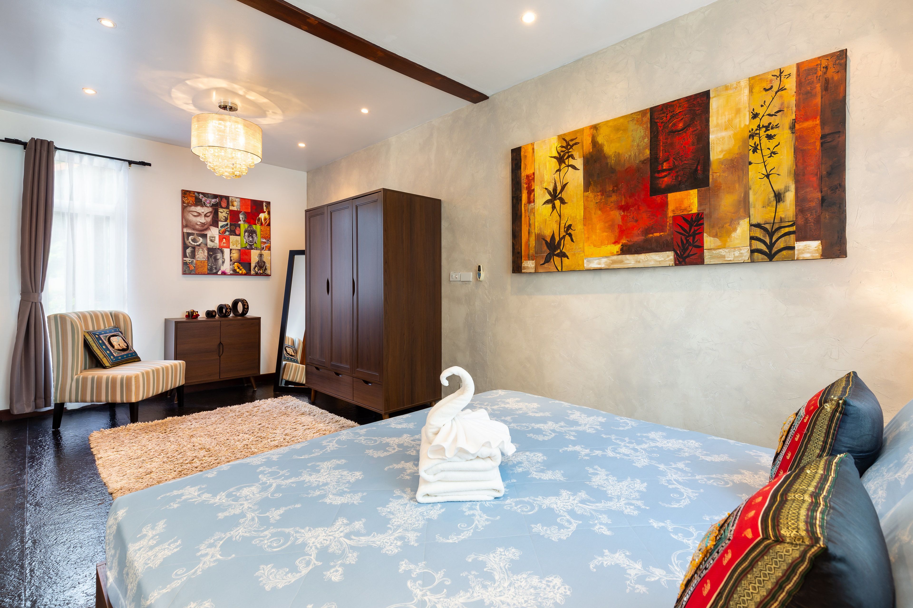 Una habitación de hotel con cama, un cuadro grande, un armario y una silla.