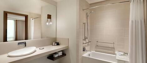 A modern bathroom with a bathtub, a sink, a mirror, and a shower.
