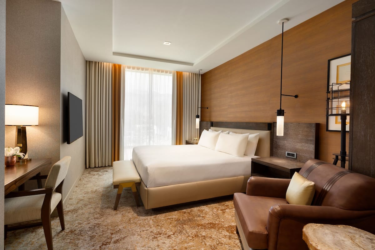 Una habitación de hotel moderna con una cama grande, un escritorio con una silla, un sofá y un televisor.