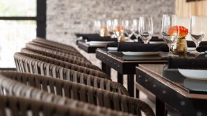 Une rangée de chaises et de tables en osier dans un coin repas, avec un mur en briques en arrière-plan.
