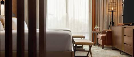 Ein Hotelzimmer mit Bett, Schreibtisch, Stuhl und Fernseher.