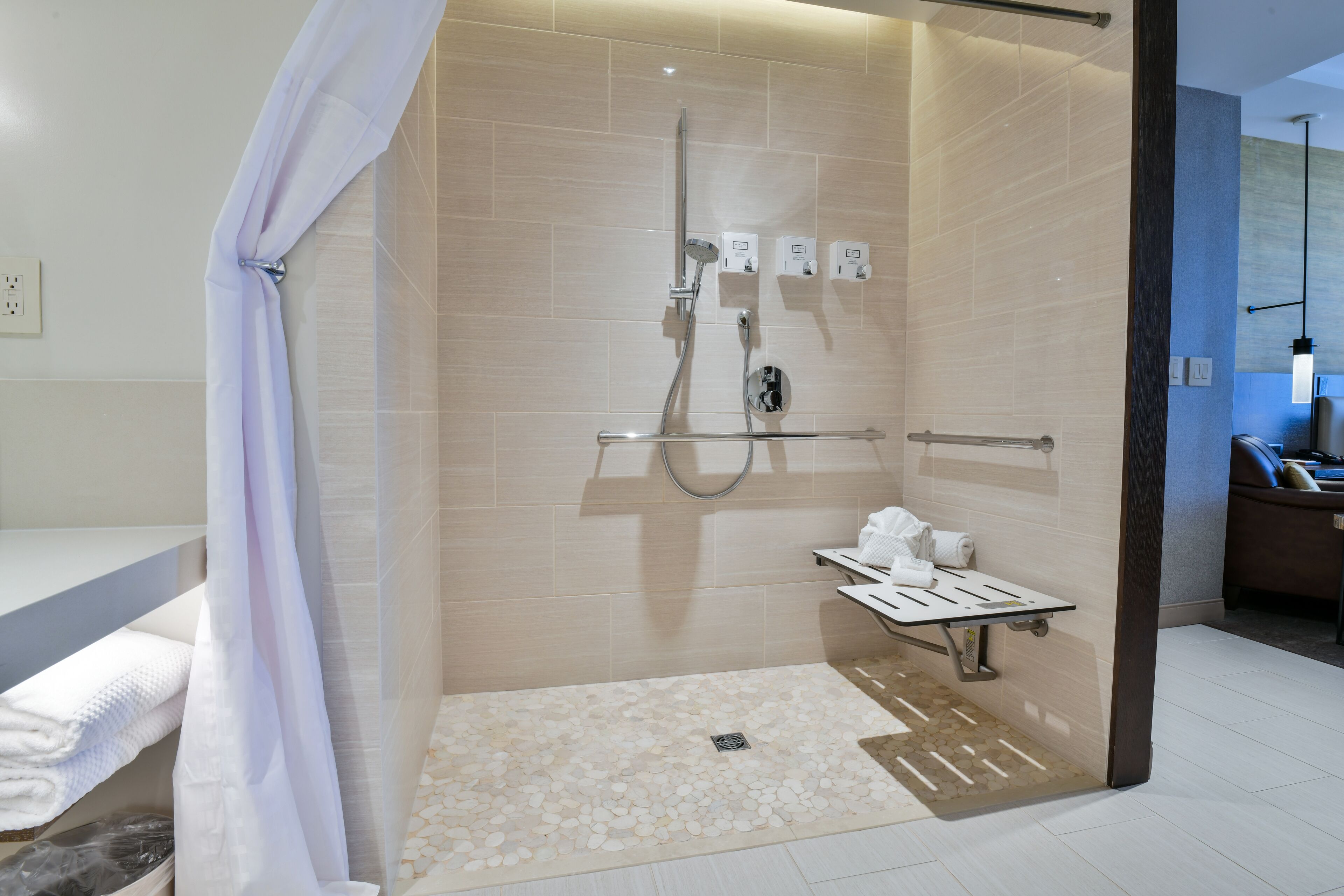 Un bagno moderno con doccia a filo pavimento, una panca e un porta asciugamani.