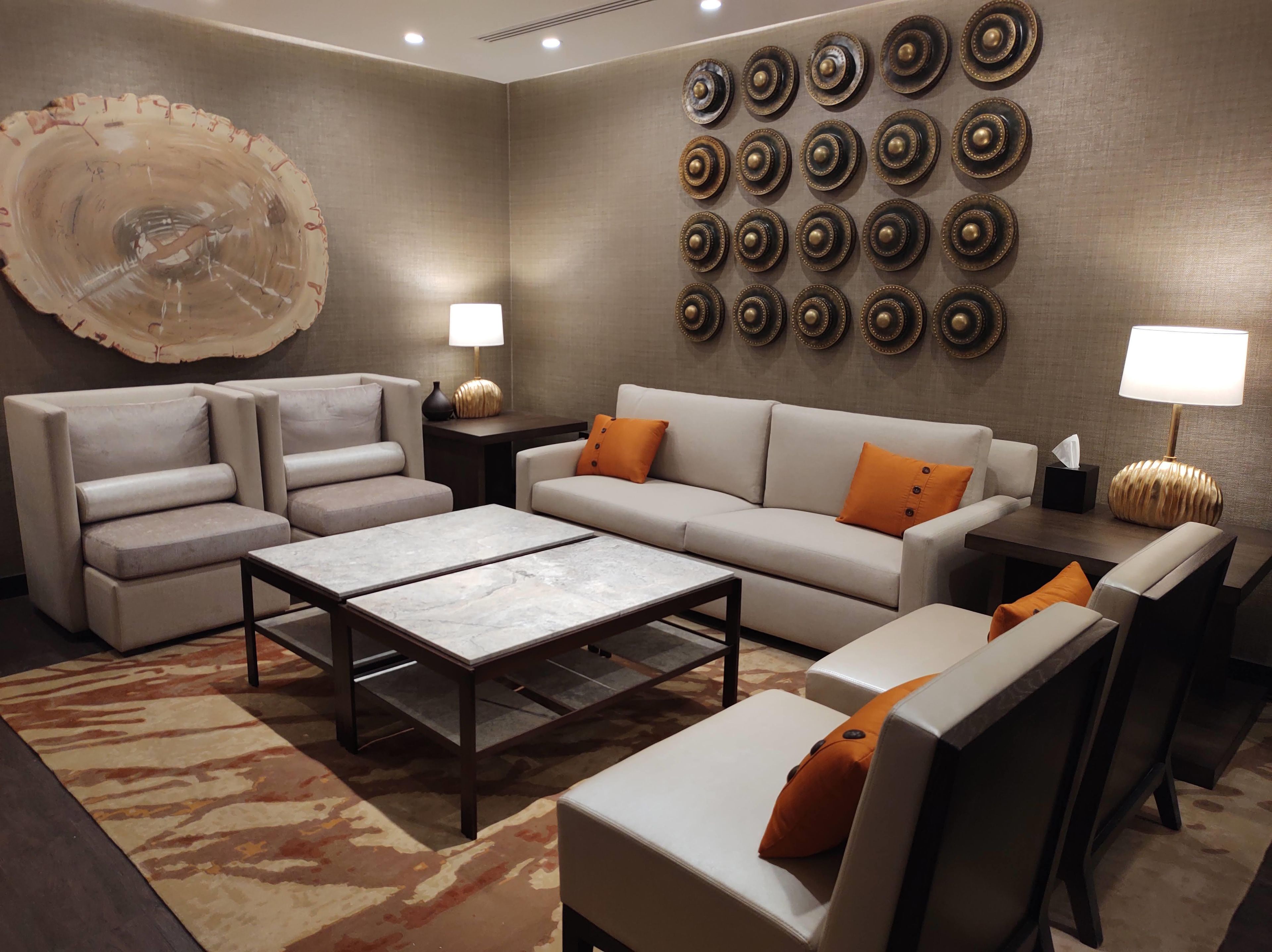 A modern living room with a sofa, armchairs, a coffee table, and a decorative wall with circular patterns.