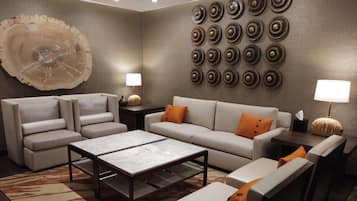 A modern living room with a sofa, armchairs, a coffee table, and a decorative wall with circular patterns.