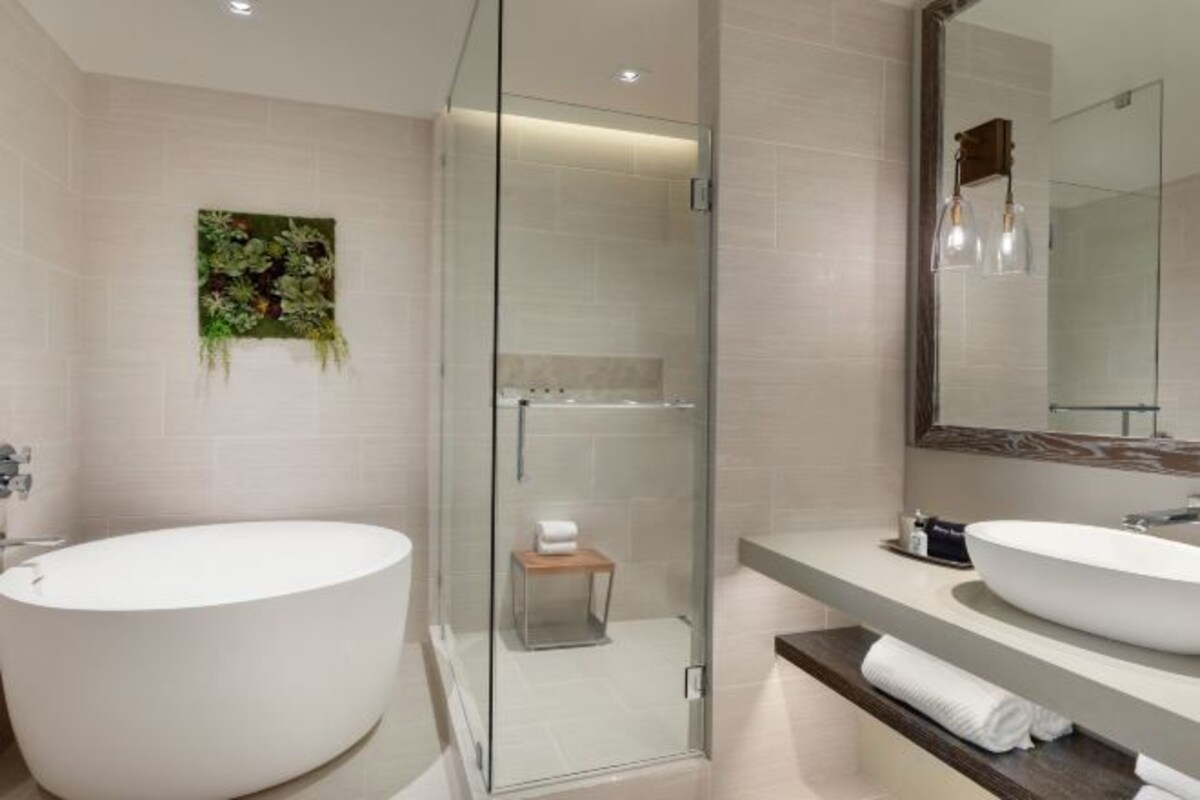 A modern bathroom with a freestanding bathtub, a glass-enclosed shower, and a large mirror above the sink.