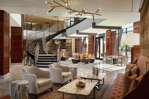 Un vestíbulo espacioso con una escalera moderna, asientos cómodos y un amplio ventanal con vistas al exterior.