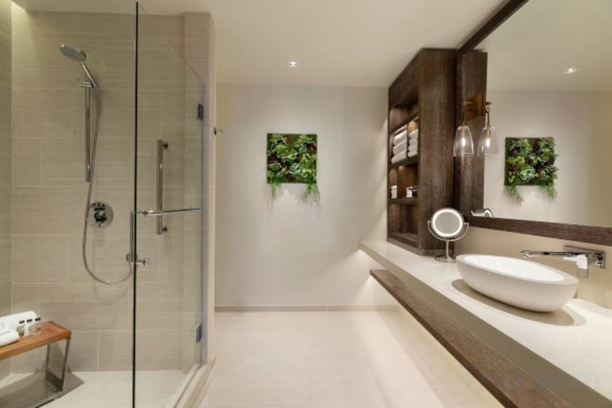 A modern bathroom with a glass shower enclosure, a large mirror, and a built-in sink.