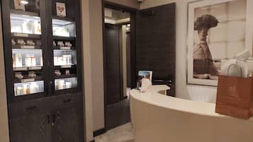 Una zona de recepción con mostrador, una vitrina con productos y un cuadro en la pared.