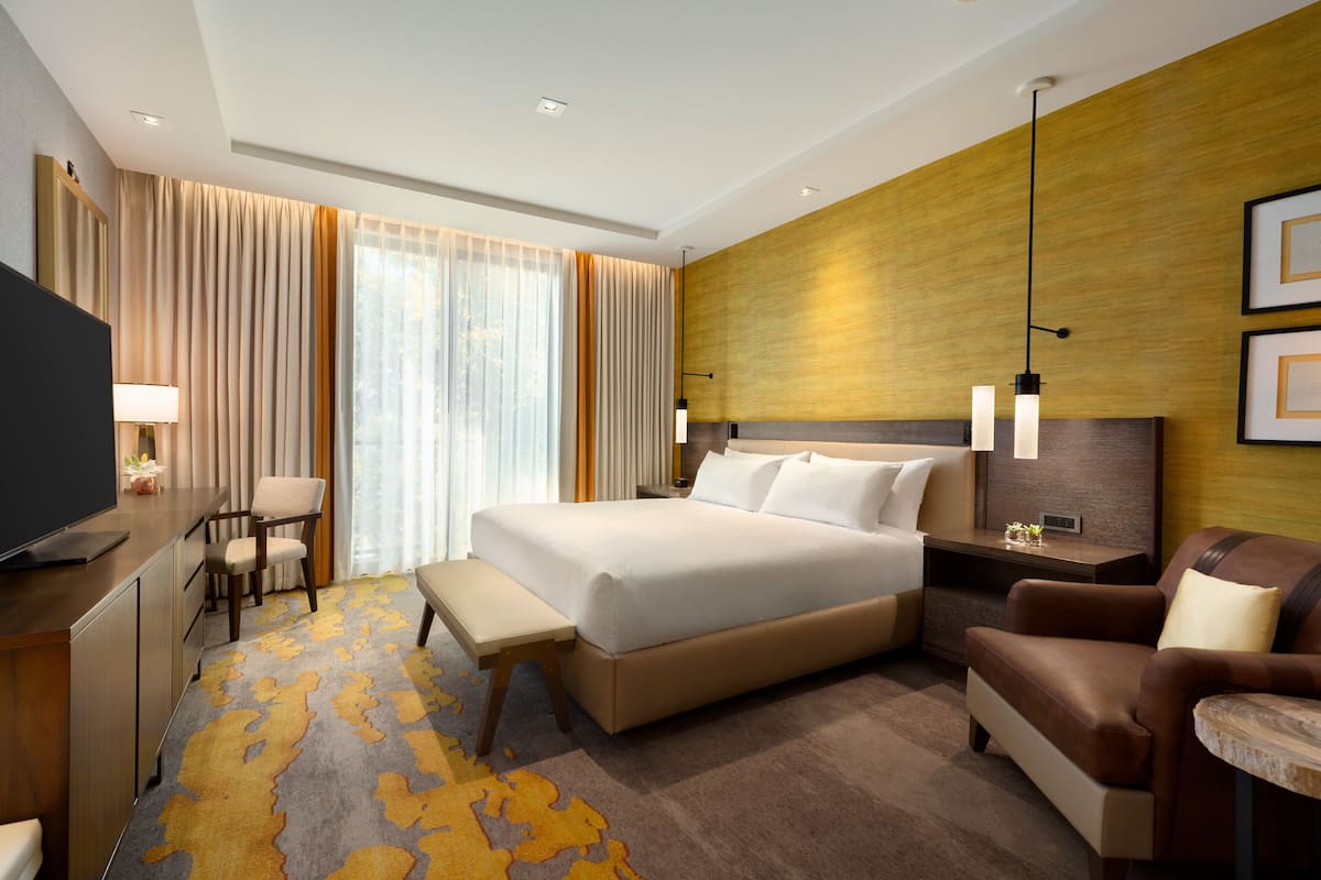 Una habitación de hotel moderna con una cama grande, un escritorio con una silla, un sofá y un televisor.