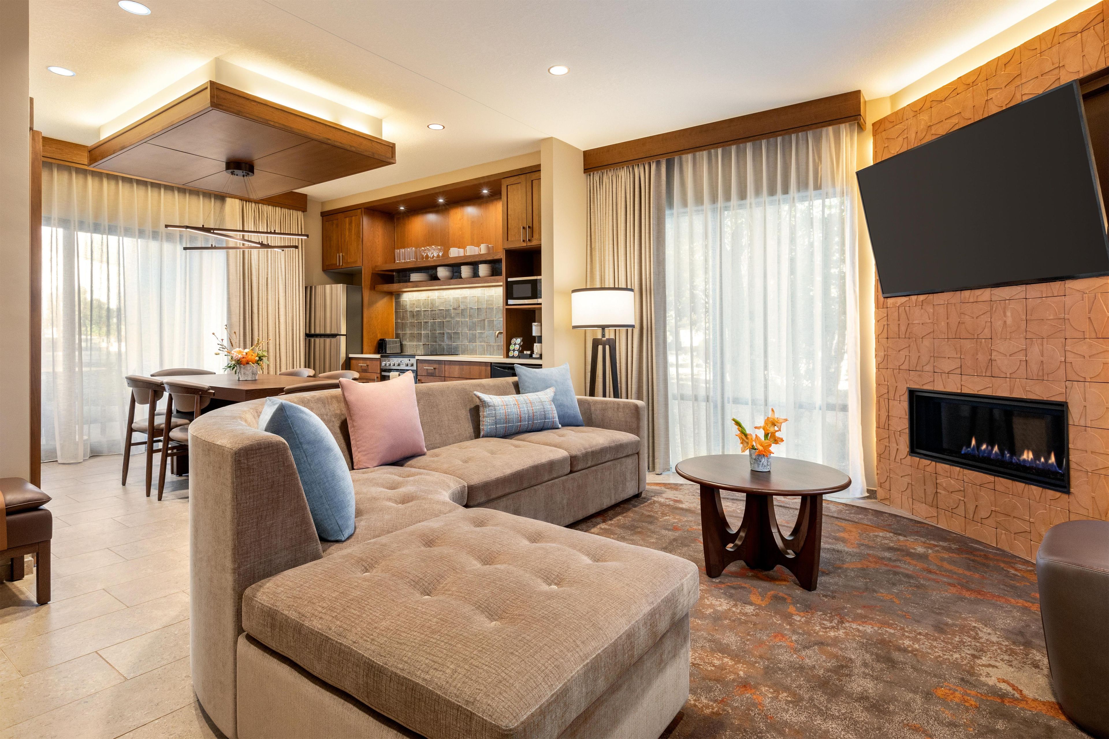 A modern living room with a sectional sofa, a dining area, and a fireplace.