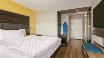 Een hotelkamer met een groot bed, een bankje, een bureau en een spiegel.