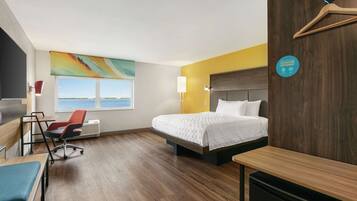 Una habitació d'hotel amb llit, escriptori, cadira i vista al mar.