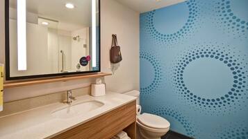 Un baño con un espejo grande, un lavabo, un inodoro y una pared con un diseño a lunares azules.