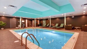 An indoor swimming pool with clear lane markings, a lifeguard chair, and lounge chairs around the pool area. - Tru by Hilton Wytheville (Wytheville)