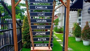 A wooden swing set with a sign listing names of flowers. - Omah Madam Bed & Breakfast (Semarang)