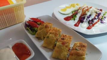 A table with a variety of dishes including a salad, a plate with eggs and a creamy sauce, and a dish with a red sauce.