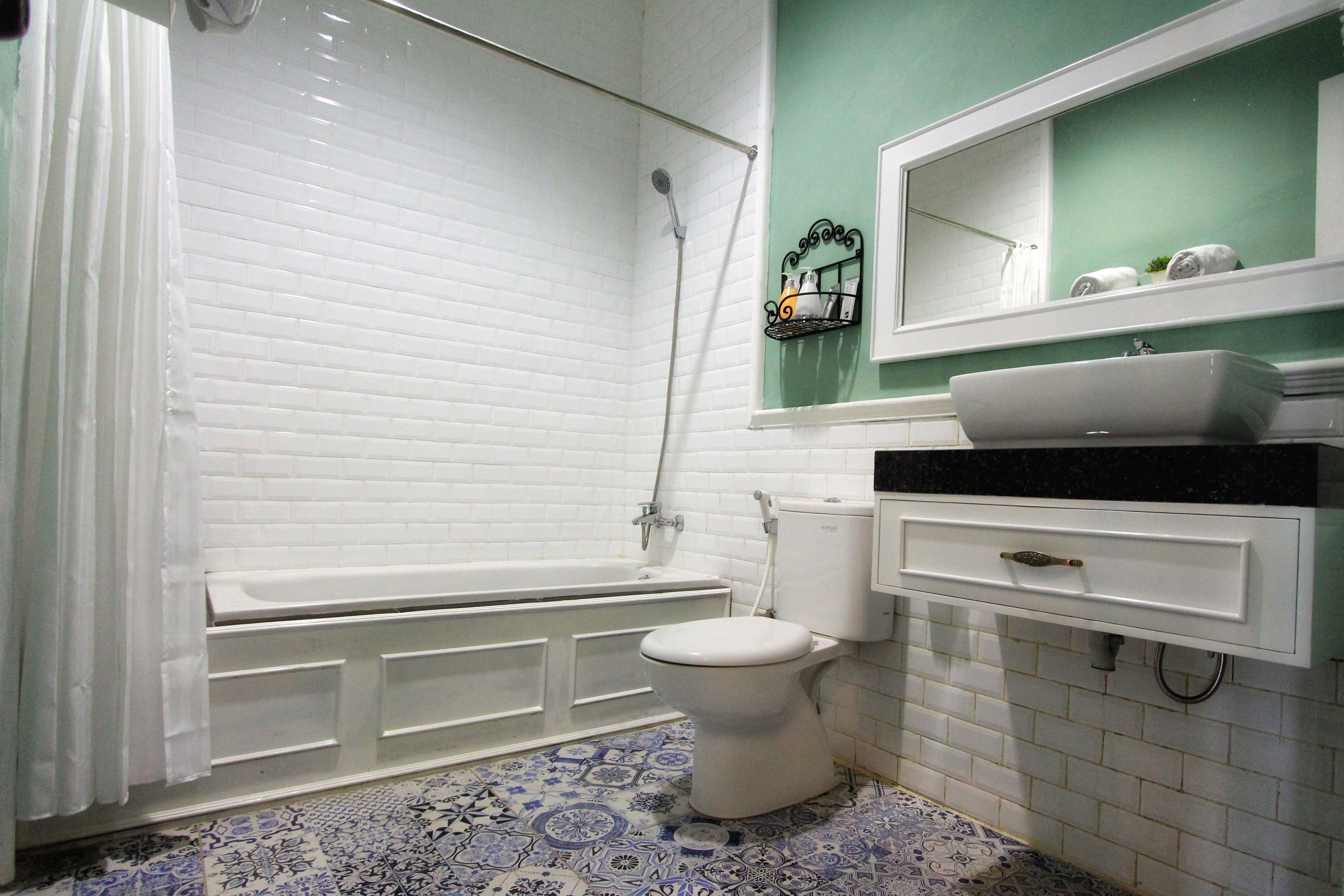 A bathroom with a white bathtub, a white toilet, a sink with a black countertop, and a mirror above the sink.